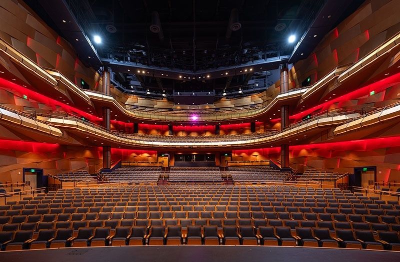 Teatersal med mange seter og flere balkonger belyst i rødt